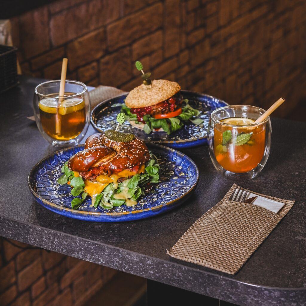 Zwei Burger auf blauen Tellern mit einem Getränk auf einem Tisch