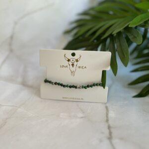 Grünes Jade Armband auf Love Ibiza Karte mit dekorativen Pflanzen im Hintergrund