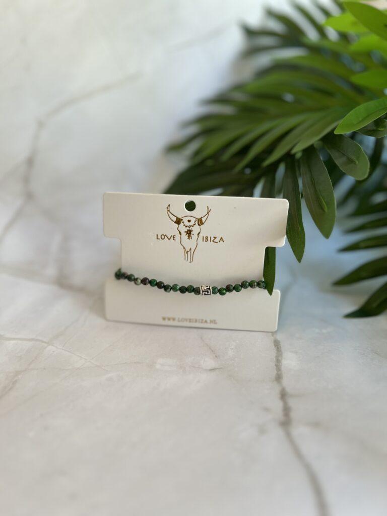 Grünes Jade Armband auf Love Ibiza Karte mit dekorativen Pflanzen im Hintergrund
