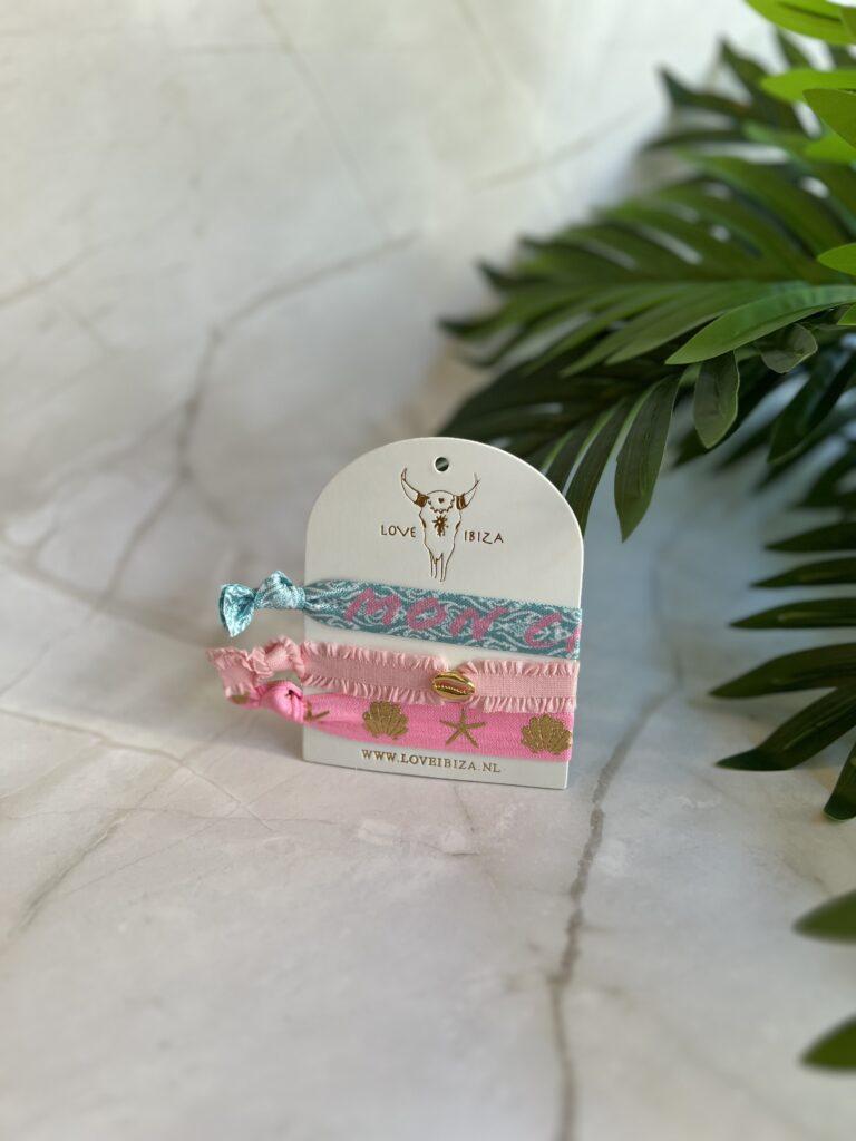 Stylische Armbänder von Love Ibiza auf einem Tisch mit grünen Pflanzen im Hintergrund