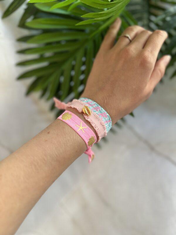 Bunte Armbänder in fröhlichen Farben an einer Hand mit tropischen Blättern im Hintergrund
