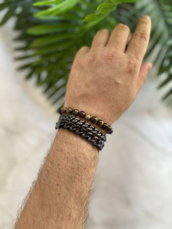 Armband mit verschiedenen Stilrichtungen auf einem Handgelenk vor Grünpflanzen.